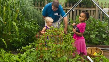 Two children in the garden learning from a master gardener