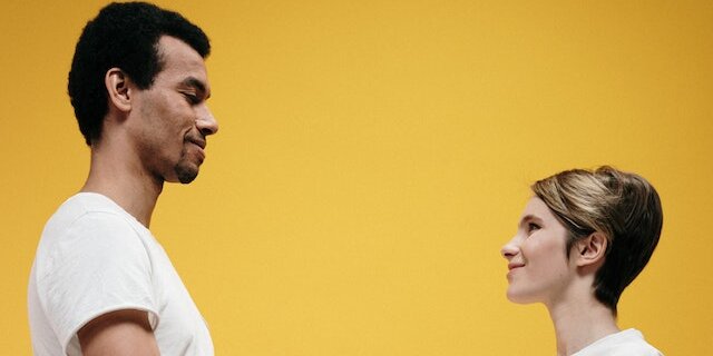 A man and woman shaking hands in front of a yellow background