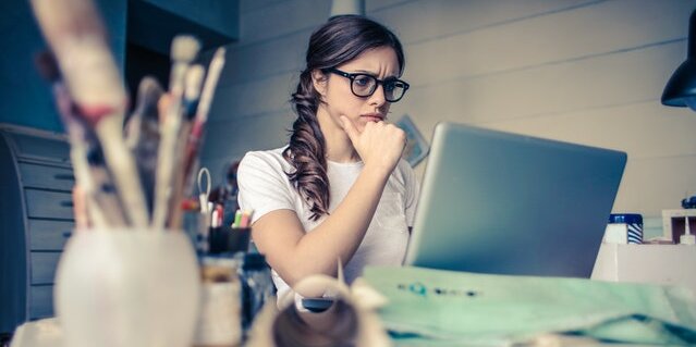 A young woman looking at her laptop, concentrating hard