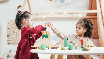 Two little girls playing with building blocks at a table