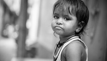 A black and white photo of a child, who looks sad