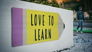 A pencil-designed sign on a brick structure that reads "Love to Learn" 