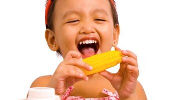 A little girl pretending like she is eating corn on the cob