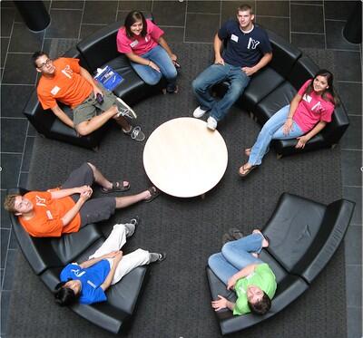 A bird's eye view of six college students sitting in the atrium of Doris Kelley Christopher Hall, looking upward